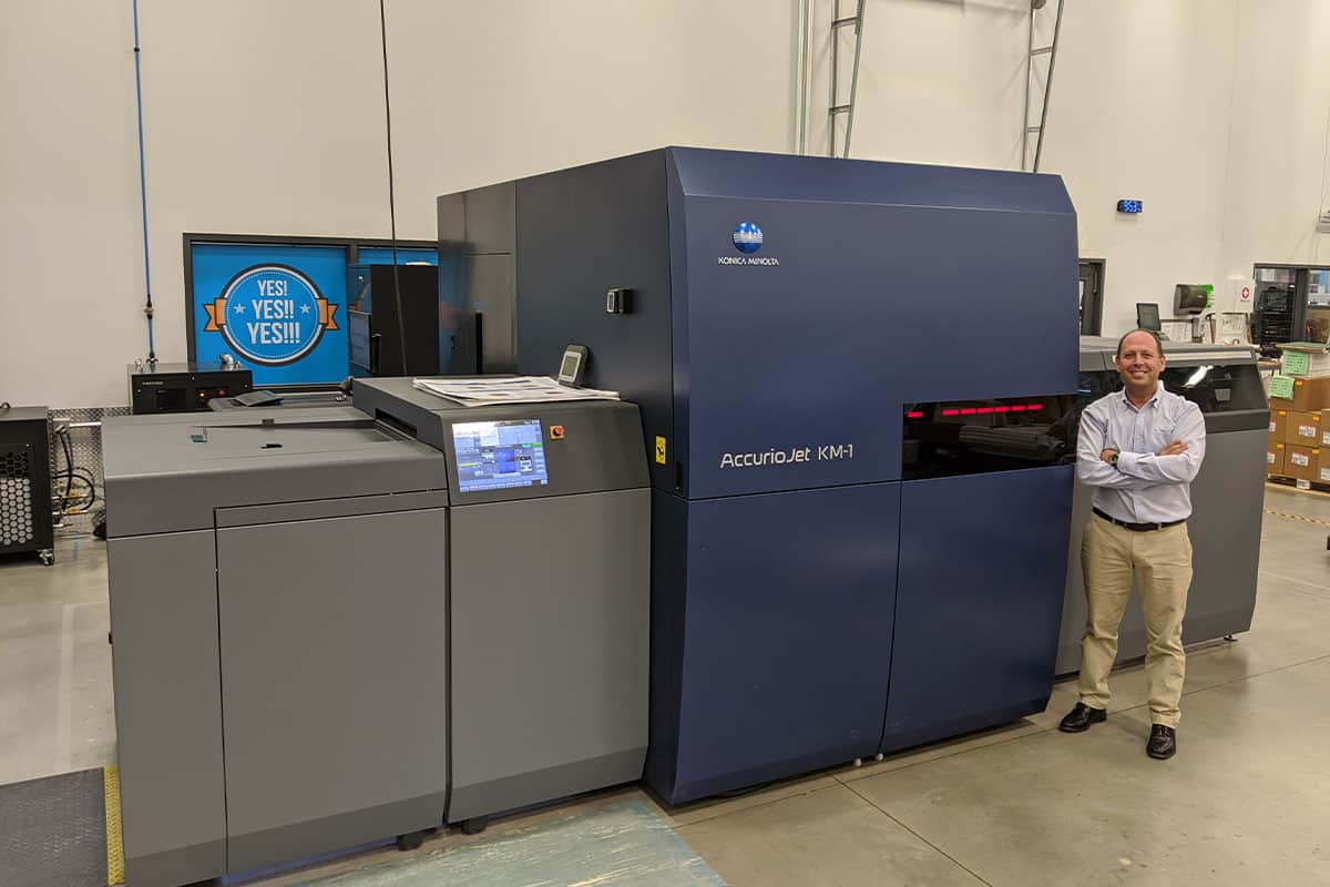 keith miller, ceo of strategic factory poses next to commercial printing equipment