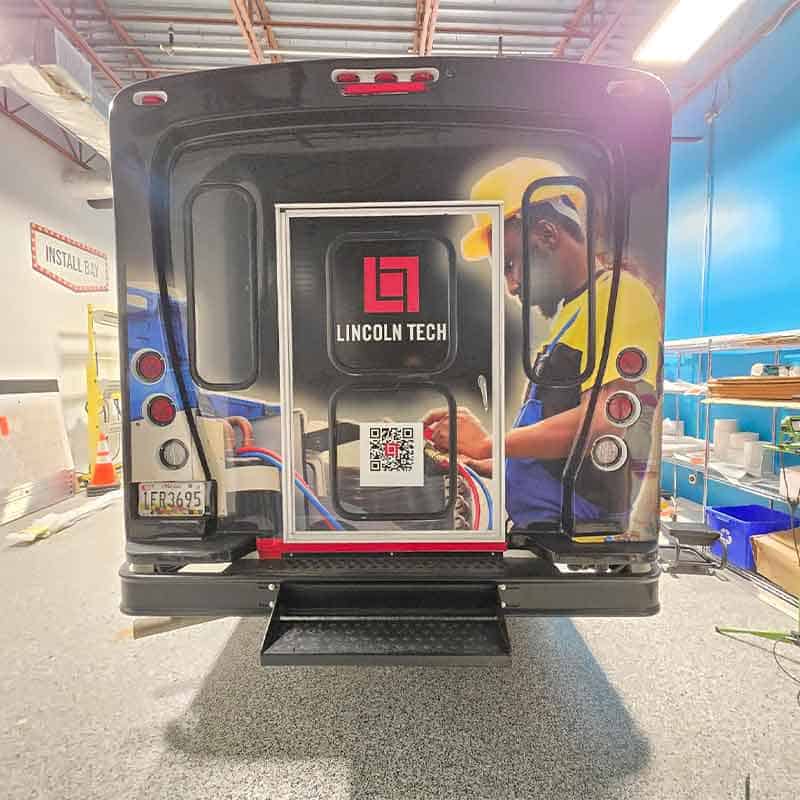 Vinyl bus wrap for Lincoln Tech made by Strategic Factory with blue collar work on the back.
